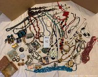 Overview of assorted necklaces, bracelets, earrings laid out on cloth