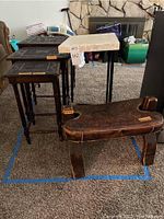Wide view of all items in the lot: three nested dark wood tables with embossed leather tops, one matching Peruvian leather stool, and a small sofa side C table with beige marble top.
