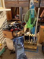Overview of lot showing wooden rack with fishing poles, green net, cooler and wheeled cart
