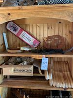 Wooden shelf with vintage Cream of Wheat thermometer, two wooden wall signs, wooden pegboards, wooden bracket pieces, a box with power strips and other small items.