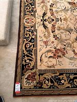 Close-up of rug corner showing ivory background, floral motif and dark decorative border