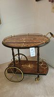 Full front view of two-tier bar cart showing drop leaf top, wheels and bottle holders