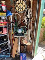 Green bench grinder on metal stand with cords and other tools around.