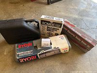 Overview of all items in the lot on floor including detail carver kit, boxed electrical wire, body saw, and carrying case