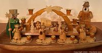 Full set of German wooden Christmas candle decor and smokers arranged on a wooden base with candle holders and figures.