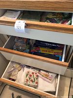 Photo showing kitchen towels and various kitchen items organized in drawers including plastic wrap, skewers, candles, and cupcake liners.