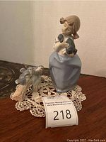 Photo showing girl figurine holding a puppy, birds figurine, and lace doily together