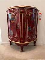 Front view of red lacquered wooden demi-lune side cabinet with floral and bird motifs