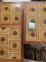 Top view of two adjacent table tops showing wood frames and tile inlay pattern