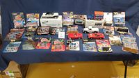 Full lot of unopened Hot Wheels, Nascar Racing Champions, and various die cast collectible vehicles displayed on table.