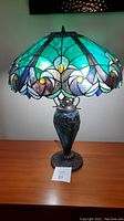 Front view of Tiffany style stained glass table lamp showing the colorful shade and bronzed metal base.