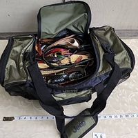 Photo showing the open Jeep-branded bag full of assorted belts in various colors and styles, along with measuring tape for scale.