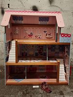 Front view of the Kidkraft wooden doll house showing all three floors with nursery and playroom decorations