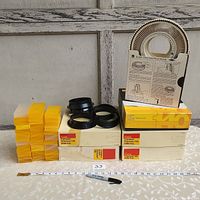 Five Kodak Carousel Transvue 140 slide trays in original Kodak boxes stacked with over 30 yellow slide cases and some black plastic parts on the table in front of a wooden door.