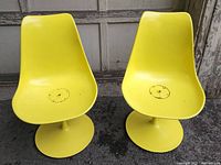 Front view of both chairs showing yellow shell seats and pedestal bases