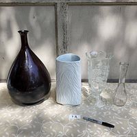 Four assorted vases shown side by side on floral tablecloth against white wooden background.