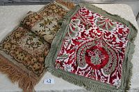 Two small vintage rugs; one with yellow floral pattern and one red patterned rug with fringes, shown laid out flat.
