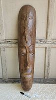Front view of the wooden carved mask showing full length and detailed carvings on forehead and face