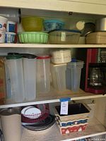 Shelf containing various Tupperware containers, plastic bowls, and Mr. Coffee coffee maker