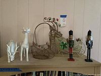 Wide view of all Christmas decor items: two white reindeer figurines, two wire metal basket reindeer with colored balls, two standing nutcracker figures.