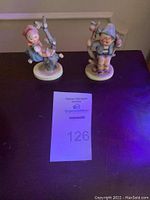 Front view of both Hummel figurines, Apple Tree Girl (#141) on left and Apple Tree Boy (#142) on right.