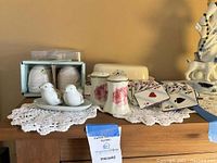 Full display with salt and pepper shakers including rose pattern, dove theme, and boxed bee-themed shakers along with card holders and butter dish