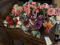 Photo showing nine silk flower arrangements with colorful blossoms including pinks, purples, and whites in various ceramic vases
