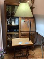 Front angle view showing table lamp with wooden top and metal magazine rack below, lampshade is beige/cream colored