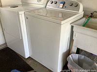 Side view of washer installed next to dryer and utility sink in garage