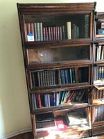 Front view of full stacking barrister bookcase with four glass-front sections and base, filled with books