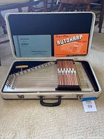 Vintage Oscar Schmidt autoharp in open case with two instruction manuals visible.