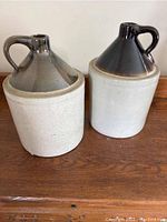 Photo showing two ceramic crocks side by side with brown glazed tops and beige crackled bodies.