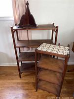 View showing both handmade wooden bookshelves and the small carved hanging shelf on top of the larger bookshelf, along with crocheted doilies on the smaller bookshelf.