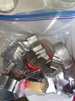 Close-up of metal cookie cutters and a wooden spoon inside a clear zip-lock bag.