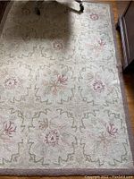 Full view of one rug showing the light brown border with green and pink floral pattern in the center.