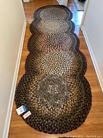 Single braided oval runner rug laid in hallway showing scalloped edges and multicolored medallions