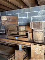 Wooden barrels, crates, boxes, and tool carrier arranged on shelving showing lot contents and condition.