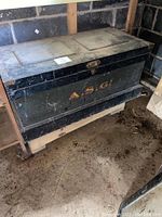 Closed exterior of rectangular wooden chest painted black with stenciled letters “A.S.G.”