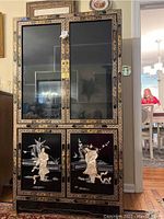Full front view of cabinet showing upper glass doors and lower lacquered doors with inlay figures