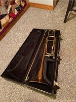 Open black hard case showing disassembled slide and bell section on plush lining