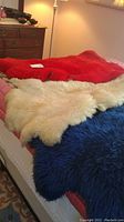 Three dyed fur pelts laid out, showing red, white, and blue colors with some wear.