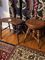 Photo of two vintage wooden stools: one round swivel piano stool with brass claw and glass ball feet, and a kidney-shaped wooden stool with turned legs.