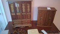 Two wooden jewelry boxes on a wooden table with jewelry pieces around.