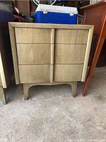 Front view of wood nightstand showing three drawers, worn finish, and mid-century modern style with tapered legs.