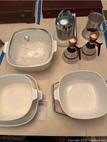 Photo showing two Corning Ware casseroles, one with glass lid, and two glass cruets with copper spouts and handles, along with a chrome cocktail shaker.