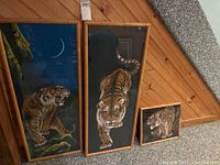 Three framed tiger themed art prints, two large vertical rectangles 44x17 inches and one smaller square 15x17 inches, arranged side by side on carpeted floor against wood-paneled wall.