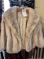 Front view of the full fur stole hanging on a wooden hanger.