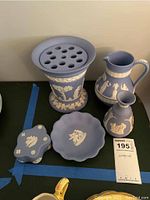 Photo showing the full set of 5 Wedgwood jasperware items on a flat black surface, including flower frog, pitchers, scalloped bowl, and lidded box.