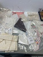 Thirteen pieces of assorted vintage linen including napkins and doilies in various colors and embroidery styles arranged on a surface.