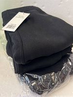 Three pairs of black faux fur lined collar blocks folded with tags visible.